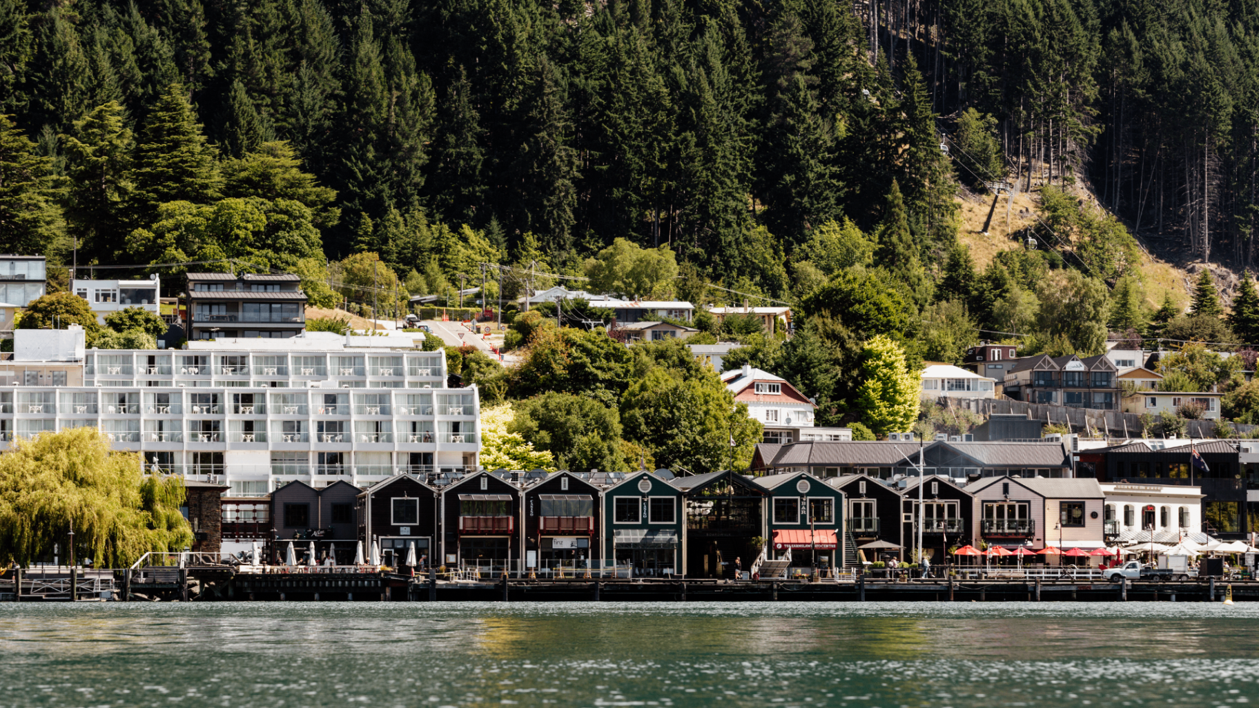 Queenstown waterfront buildings with dense green hillside behind them