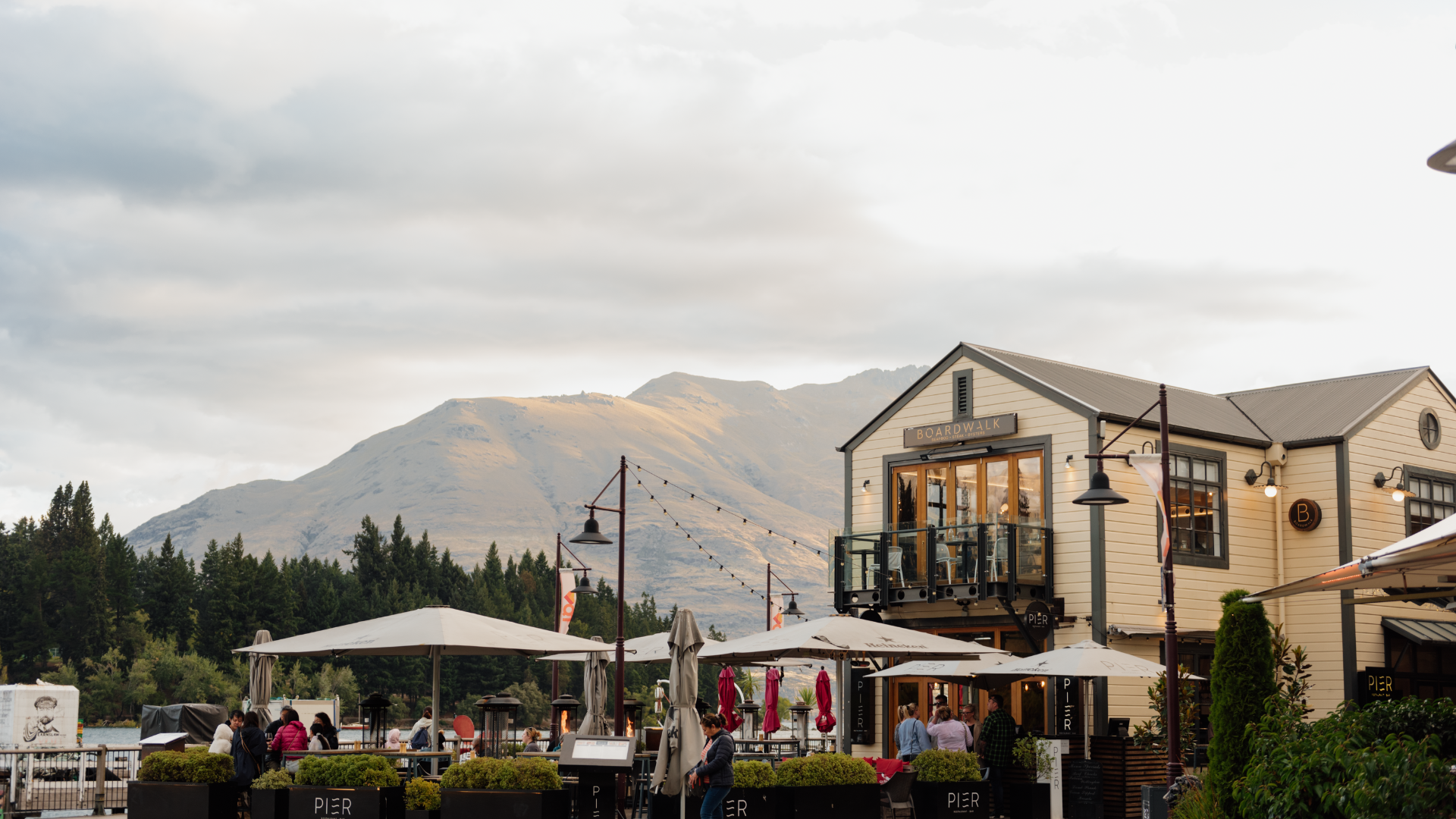 Lakefront boardwalk dining scene with mountains rising behind Queenstown