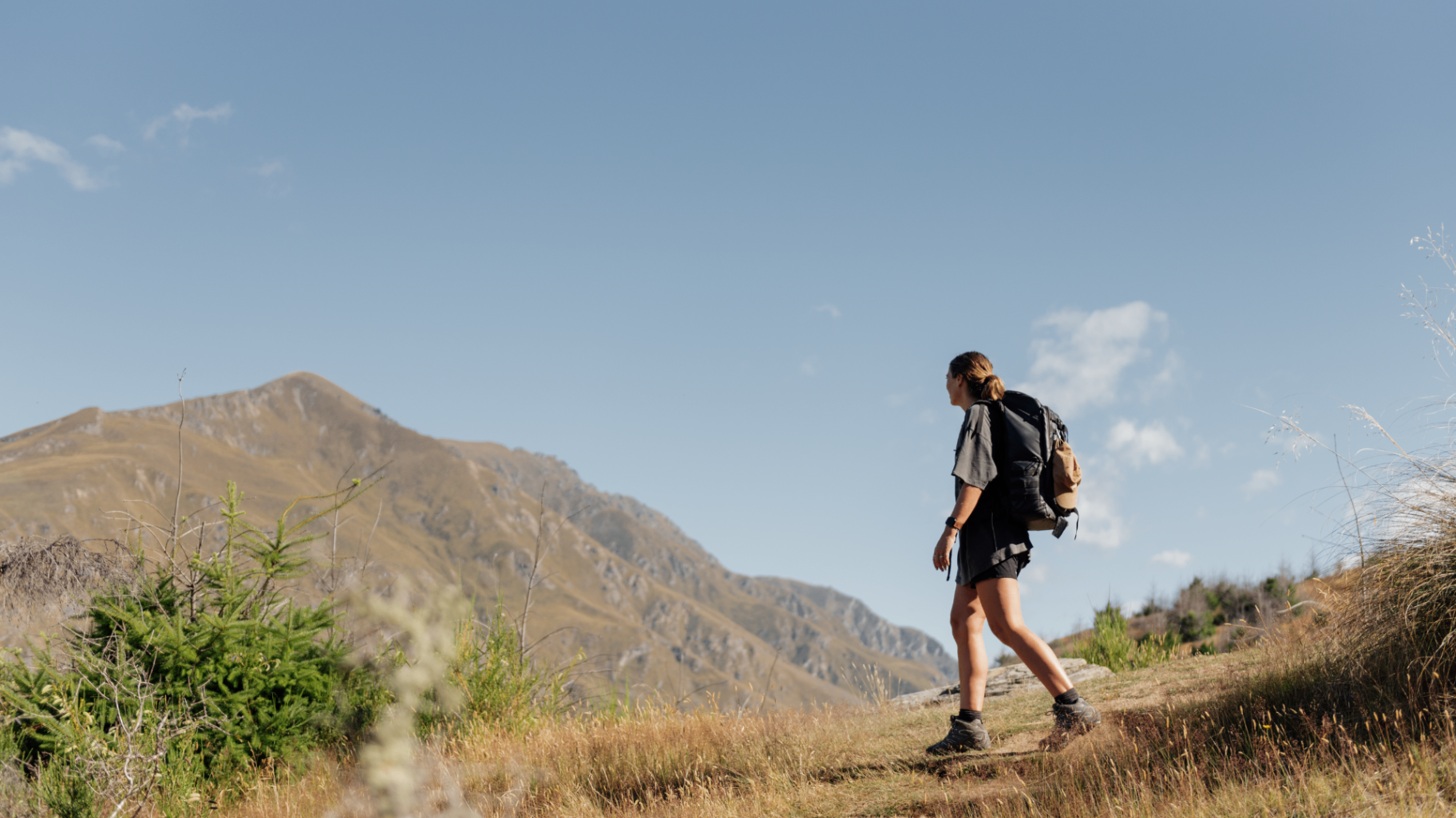 Hiker on a Queenstown hillside with alpine views