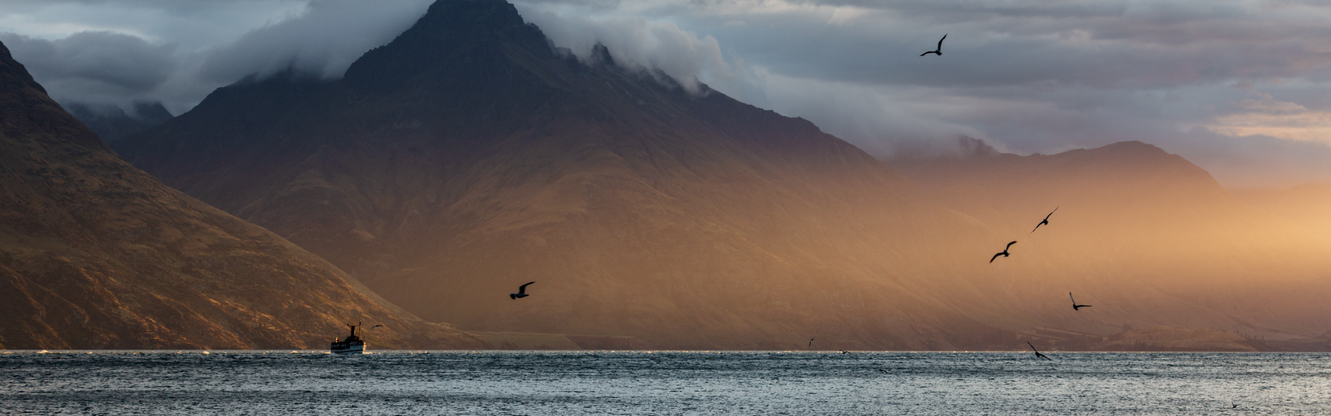 The TSS Earnslaw steamer crossing Lake Wakatipu at dusk with mountains behind